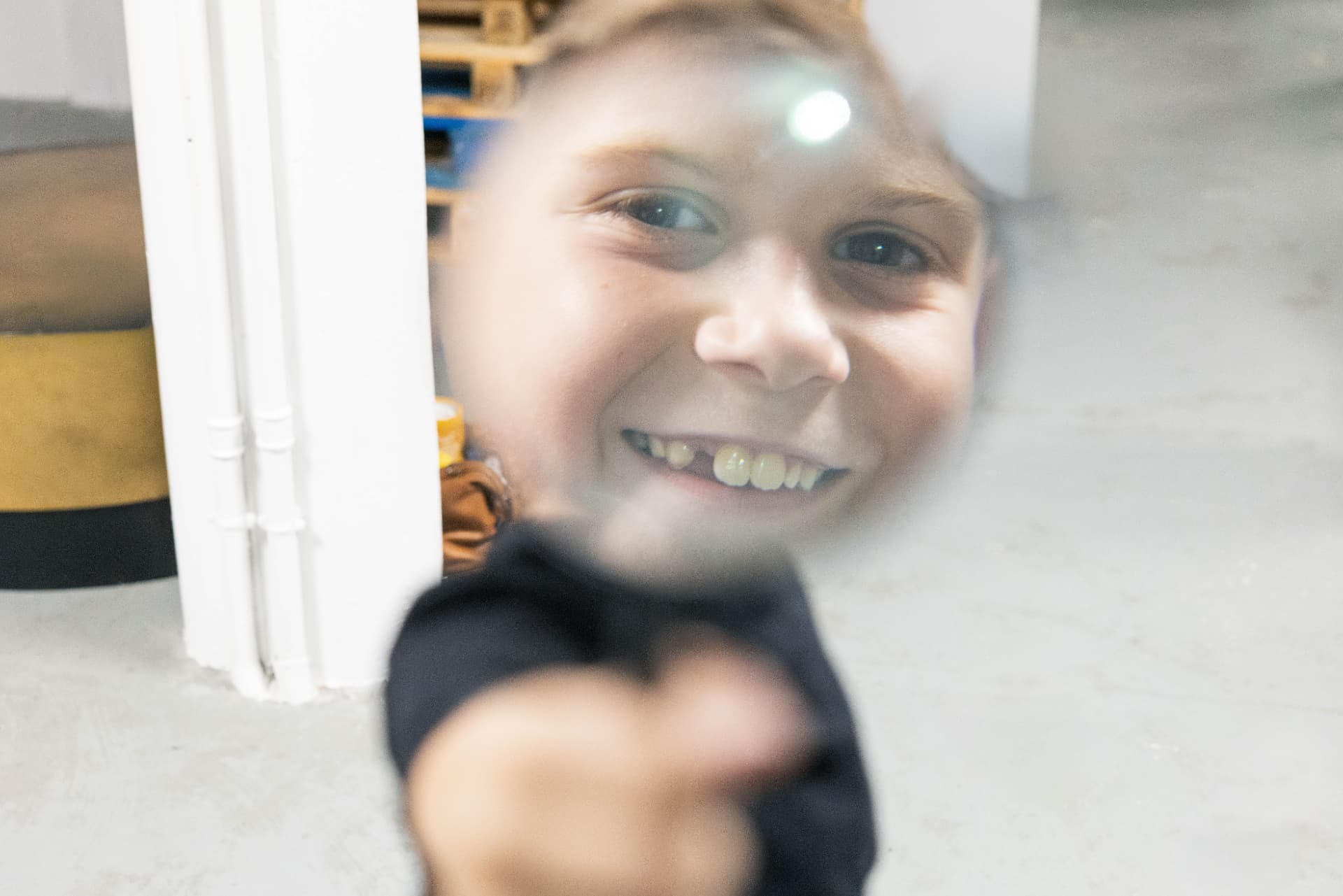 Un enfant souriant regardé à travers une loupe pendant un atelier du Labo