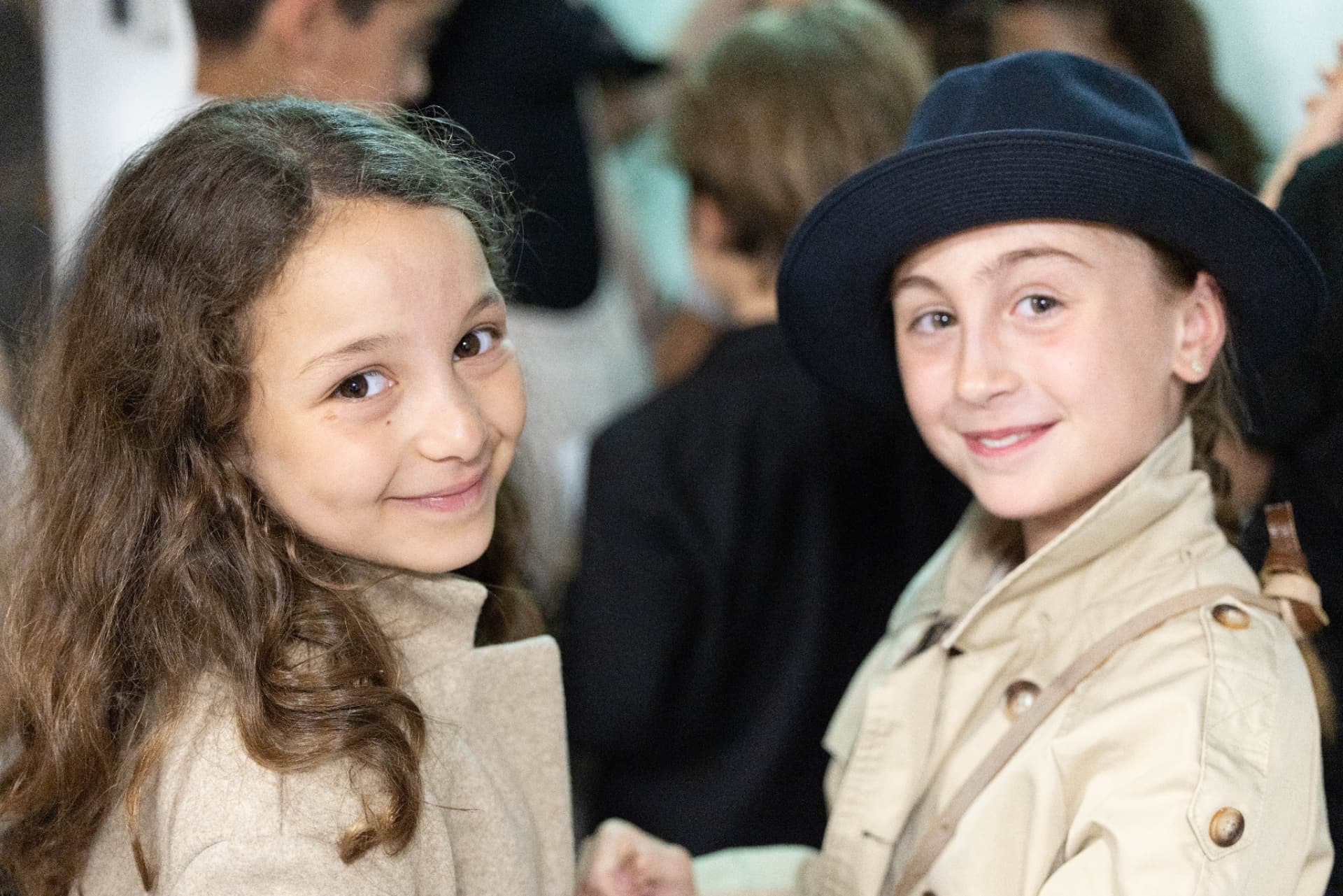 Deux enfants en costume de trench et chapeau, souriant avant d'entrer en scène